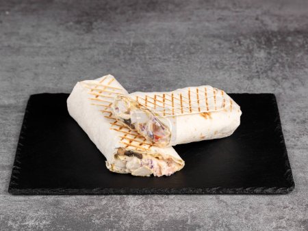 Téléchargez les photos : Rouleau shawarma dans la lavande avec poulet et champignons, légumes frais, sauce à la crème et frites sur un fond en bois. Concentration sélective - en image libre de droit
