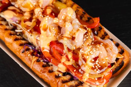 Téléchargez les photos : Hot-dogs grillés gastronomiques aux crevettes, sauce et poivrons, oignons et frittes.Hot-dogs savoureux frais - en image libre de droit