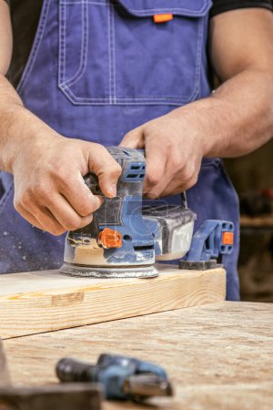 Foto de El trabajador muele la madera de la rectificadora angular - Imagen libre de derechos