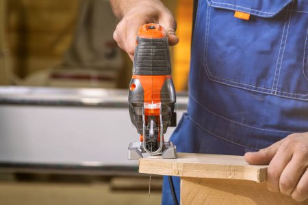 Foto de Un carpintero usando un rompecabezas para cortar madera corta barras. Conceptos de reparación del hogar, primer plano. - Imagen libre de derechos