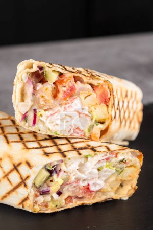 Téléchargez les photos : Bâtonnets de crabe fraîchement préparés shawarma, sauce et légumes sur une planche en bois - en image libre de droit