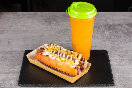 Téléchargez les photos : Hot dog avec saucisses, oignons, chips, légumes et salade et boisson sur un fond en bois. Vue d'en haut - en image libre de droit
