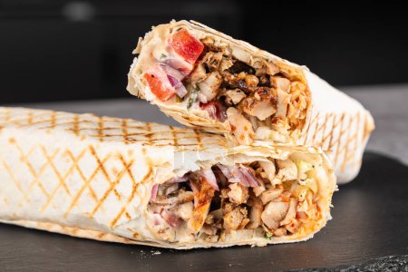 Téléchargez les photos : Shawarma de poulet, rouleau frais, pellicule de viande grillée et pellicule de laitue avec sauce blanche. Donateur turc Kebab sur pain pita - poulet Shawarma. - en image libre de droit