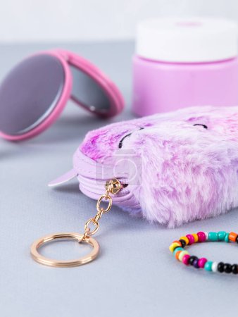 Foto de Un regalo para una niña, un niño, un perfume, una billetera infantil en forma de unicornio en rosa, pegatinas cercanas, un llavero, un espejo, cuentas y otras cosas de los niños - Imagen libre de derechos