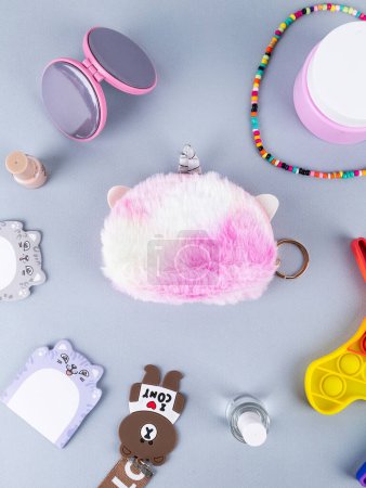 Téléchargez les photos : Un cadeau pour une fille, un enfant, un parfum, un portefeuille pour enfants en forme de licorne en rose, des autocollants à proximité, un porte-clés, un miroir, des perles et autres objets pour enfants - en image libre de droit