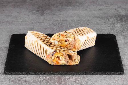 Téléchargez les photos : Rouleau Shawarma à la lavande avec poulet, légumes frais, sauce à la crème et frites sur fond de bois. Concentration sélective - en image libre de droit