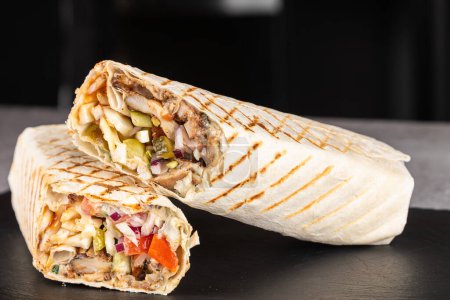 Téléchargez les photos : Shawarma rouler dans la lavande avec des bâtonnets de crabe, légumes frais, sauce à la crème et frites sur un fond en bois. Concentration sélective - en image libre de droit
