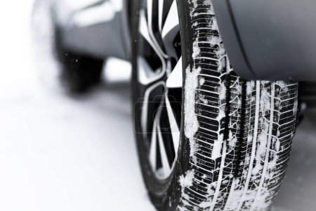 Foto de Primer plano de un neumático de invierno. Detalle de neumáticos de coche en invierno en una carretera cubierta de nieve. - Imagen libre de derechos