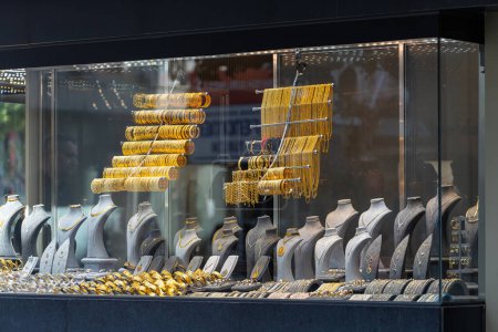Téléchargez les photos : Vitrine d'une bijouterie avec une vaste sélection de bracelets, chaînes, bagues et boucles d'oreilles en or sur un relief féminin - en image libre de droit