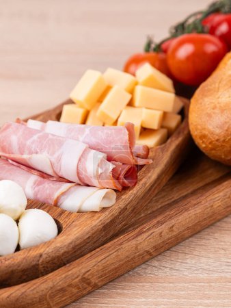 Photo for Wooden tray, menazhnitsa with cheese, sausage and vegetables, close-up on a wooden background - Royalty Free Image