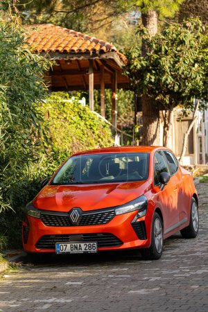 Foto de Lado; Turquía 04 de febrero 2024: naranja Renault Megane está estacionado en la calle en un día cálido con el telón de fondo del parque - Imagen libre de derechos
