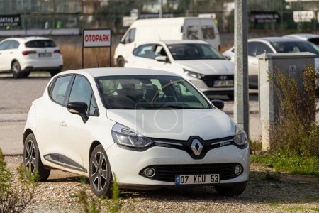 Téléchargez les photos : Côté Turquie 04 Février 2024 : Renault Clio blanche est garée dans la rue par une chaude journée d'été sur fond de parc - en image libre de droit