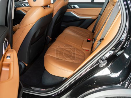 Foto de Novosibirsk, Rusia - 04 de febrero de 2024: BMW X5 negro, primer plano de los asientos traseros de color naranja con cinturón de seguridad. interior del coche moderno - Imagen libre de derechos
