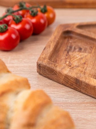 Photo for Close-up of a wooden oak plate with vegetables and bread in the background - Royalty Free Image