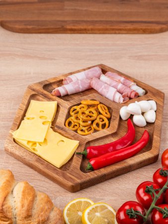 Foto de Bandeja de madera con quesos variados, salchichas y verduras. Plato de queso, aperitivos para la mesa de vacaciones. - Imagen libre de derechos