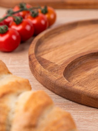Foto de Menazhnitsa plato vacío hecho a mano sobre una mesa de madera decorada con verduras y pan - Imagen libre de derechos