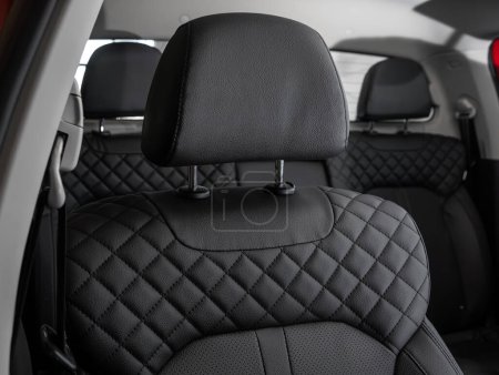 Photo for Close-up  leather black  rear seat made of  in the background passenger seats with seat belts. Luxury car interior - Royalty Free Image
