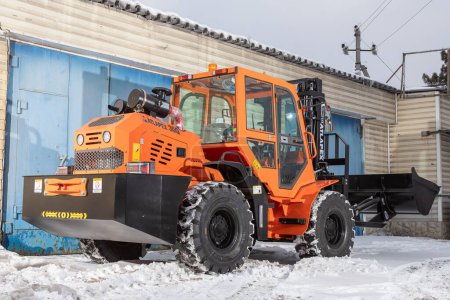 Téléchargez les photos : Novossibirsk, Russie - 29 Février 2024 : Tracteur orange, chargeur contre garage - en image libre de droit