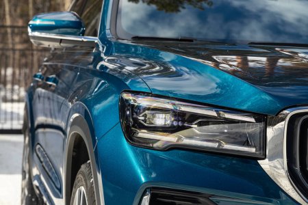 Téléchargez les photos : Phare d'une voiture bleue populaire moderne gros plan. Phare de voiture en verre brillant avec éblouissement de la lumière - en image libre de droit