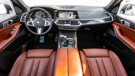 Foto de Novosibirsk, Rusia - 23 de marzo de 2024: BMW X7 negro, Interior de un nuevo SUV moderno con volante, palanca de cambios y tablero de instrumentos, control de temperatura, velocímetro, pantalla. Interior de cuero rojo - Imagen libre de derechos