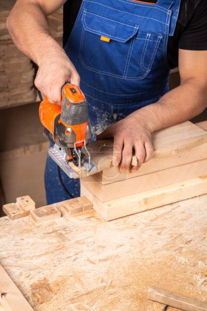 Photo for A carpenter using a jigsaw to cut wood cuts bars. - Royalty Free Image