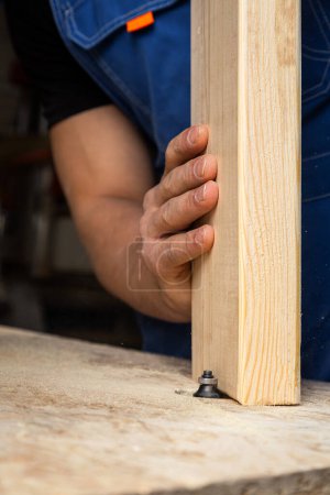 Foto de Un carpintero joven equivale a una barra de madera con una fresadora en el taller - Imagen libre de derechos