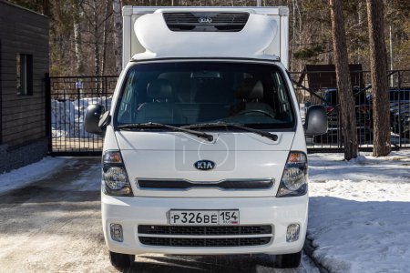 Photo for Novosibirsk, Russia - March   18, 2024 :white Kia Bongo   is parked on the street on a warm  winter  day against the  park - Royalty Free Image