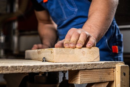 Foto de Un carpintero joven equivale a una barra de madera con una fresadora en el taller - Imagen libre de derechos
