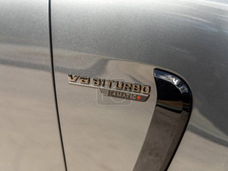 Foto de Novosibirsk, Rusia - 23 de abril de 2024: Mercedes-Benz AMG GT 63 S 4MATIC plateado, primer plano del logo V8 Biturbo en el cuerpo - Imagen libre de derechos