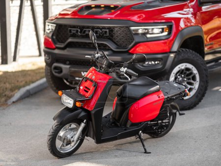 Photo for Novosibirsk, Russia -  May 01  , 2024:   red  moped Yamaha Gear , front view, parking in a car dealership with a red pickup   Dodge Ram Trx  in the background - Royalty Free Image