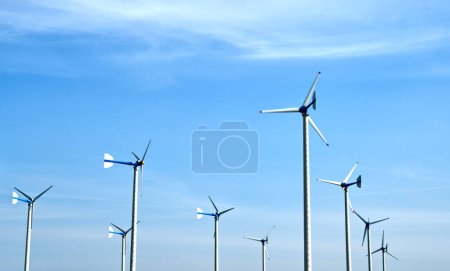 Téléchargez les photos : Les moulins à vent sont actifs sous la lumière du soleil avec le fond de beau ciel, l'image du paysage des moulins à vent, et des concepts pour l'énergie verte. - en image libre de droit