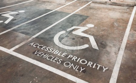 Cierre el letrero en el piso del estacionamiento solo para vehículos prioritarios accesibles, vista de perspectiva.