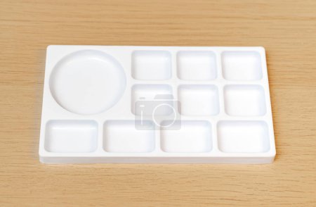 Photo for White watercolor palette. Empty watercolor tray isolated on wood background. White plastic paint palette. - Royalty Free Image