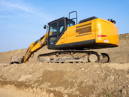 Construction machine in action: bulldozer on mound of earth