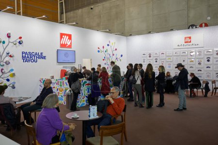 Foto de TURÍN, ITALIA - 04 DE NOVIEMBRE DE 2022: Stand de café Illy con gente y obra de arte de Pascale Marthine Tayou en Artissima 2022, vernissage feria de arte contemporáneo - Imagen libre de derechos