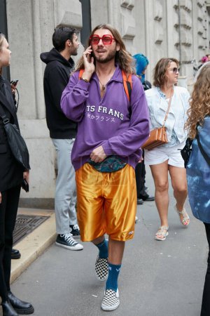Téléchargez les photos : MILAN, ITALIE - 21 SEPTEMBRE 2022 : Homme avec pull violet et short en satin jaune avant le défilé Calcaterra, Milan Fashion Week street style - en image libre de droit