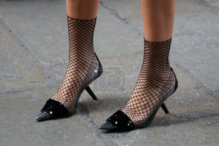 Téléchargez les photos : MILAN, ITALIE - 22 SEPTEMBRE 2022 : Femme avec des chaussettes en filet noir et des chaussures à talons hauts avec partie transparente avant le défilé de mode Dsquared2, Milan Fashion Week street style - en image libre de droit