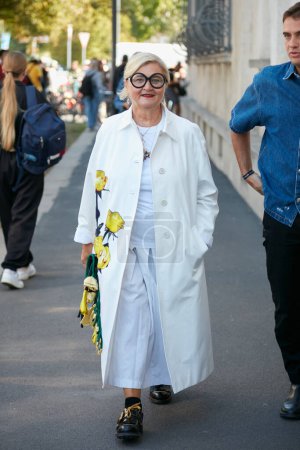 Foto de MILÁN, ITALIA - 22 DE SEPTIEMBRE DE 2022: Mujer con abrigo blanco con rosas amarillas antes del desfile de moda Prada, Milan Fashion Week street style - Imagen libre de derechos