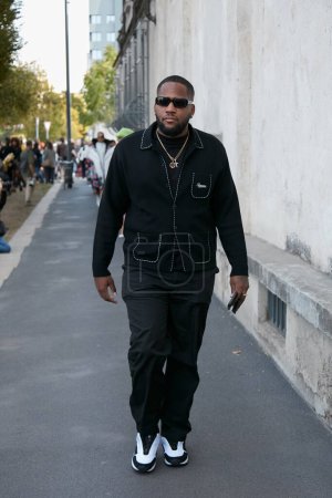 Foto de MILÁN, ITALIA - 22 DE SEPTIEMBRE DE 2022: Hombre con chaqueta negra Supreme y pantalones antes del desfile de moda Prada, Milan Fashion Week street style - Imagen libre de derechos