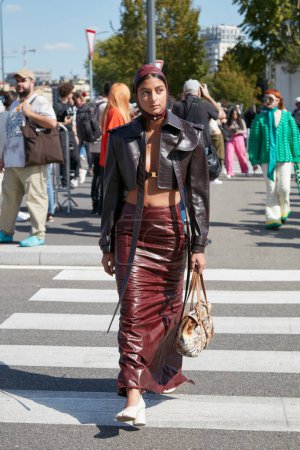 Foto de MILÁN, ITALIA - 22 DE SEPTIEMBRE DE 2022: Mujer con chaqueta marrón de cuero y falda larga de color burdeos antes del desfile de moda Prada, Milan Fashion Week street style - Imagen libre de derechos