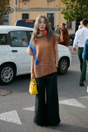 Foto de MILÁN, ITALIA - 23 DE SEPTIEMBRE DE 2022: Mujer con pantalones negros y cuello alto marrón antes del desfile de moda Tods, Milan Fashion Week street style - Imagen libre de derechos