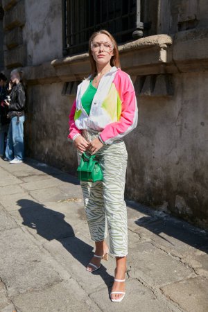 Foto de MILÁN, ITALIA - 23 DE SEPTIEMBRE DE 2022: Mujer con chaqueta de chándal blanco, rosa, amarillo y pantalones a rayas de cebra antes del desfile de moda Sportmax, Milan Fashion Week street style - Imagen libre de derechos