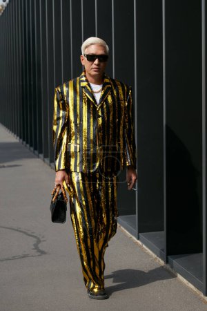 Téléchargez les photos : MILAN, ITALIE - 23 SEPTEMBRE 2022 : Bryan Boy avec veste et pantalon à rayures dorées et noires avant le défilé Gucci, Milan Fashion Week street style - en image libre de droit