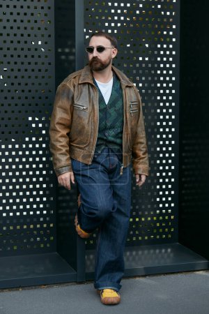 Téléchargez les photos : MILAN, ITALIE - 23 SEPTEMBRE 2022 : Christian De Gennaro avec veste en cuir marron et pantalon en denim bleu avant le défilé Gucci, Milan Fashion Week street style - en image libre de droit