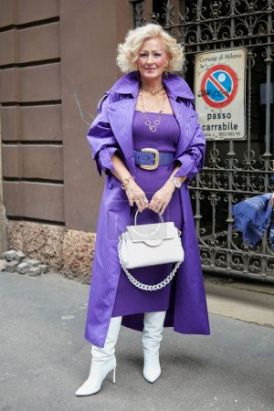 Téléchargez les photos : MILAN, ITALY - SEPTEMBER 25, 2022: Woman with purple dress, trench coat and white Versace bag before Luisa Spagnoli fashion show, Milan Fashion Week street style - en image libre de droit