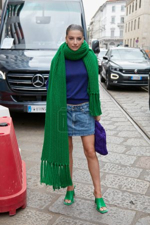 Foto de MILAN, ITALY - SEPTEMBER 25, 2022: Woman with green wool scarf and blue denim skirt before Luisa Spagnoli fashion show, Milan Fashion Week street style - Imagen libre de derechos