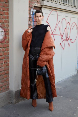 Téléchargez les photos : MILAN, ITALY - JANUARY 14, 2023: Man with brown padded long coat and black leather trousers before Fendi fashion show, Milan Fashion Week street style - en image libre de droit