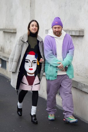 Photo for MILAN, ITALY - JANUARY 15, 2023: Woman and man with gray fur and purple and turquoise soft gradient sweater before Prada fashion show, Milan Fashion Week street style - Royalty Free Image