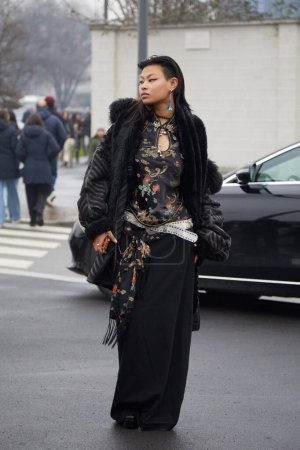 Photo for MILAN, ITALY - JANUARY 15, 2023: Woman with black fur jacket and oriental design shirt before Prada fashion show, Milan Fashion Week street style - Royalty Free Image