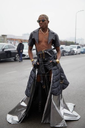 Foto de MILAN, ITALY - JANUARY 15, 2023: Man with long silver skirt and black leather shorts and shirt before Prada fashion show, Milan Fashion Week street style - Imagen libre de derechos